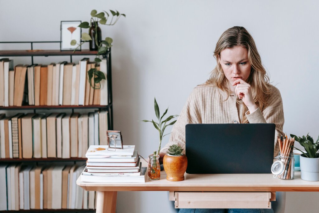 Focused woman working on laptop at home office desk