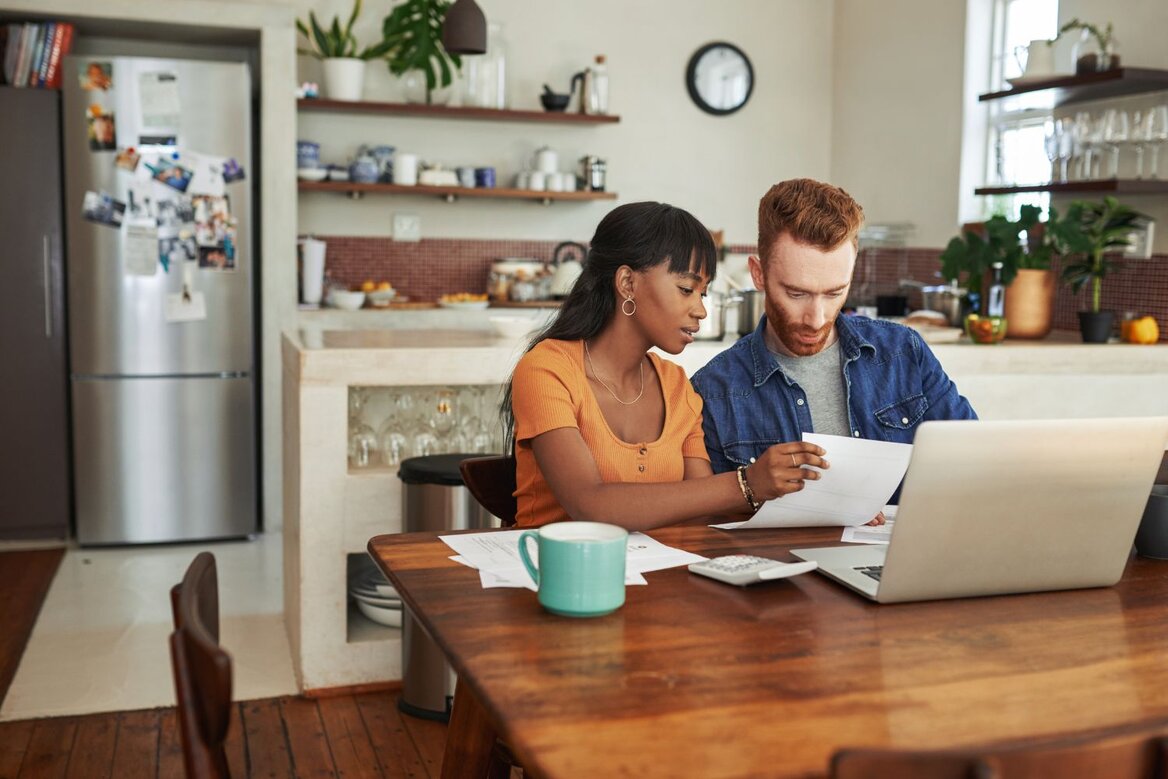 Couple reviewing tax documents and finances at home using a laptop