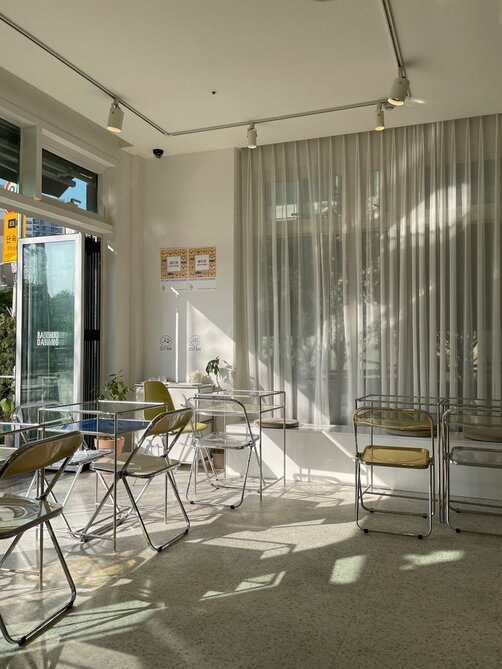 Bright minimalist café interior with folding chairs and curtains