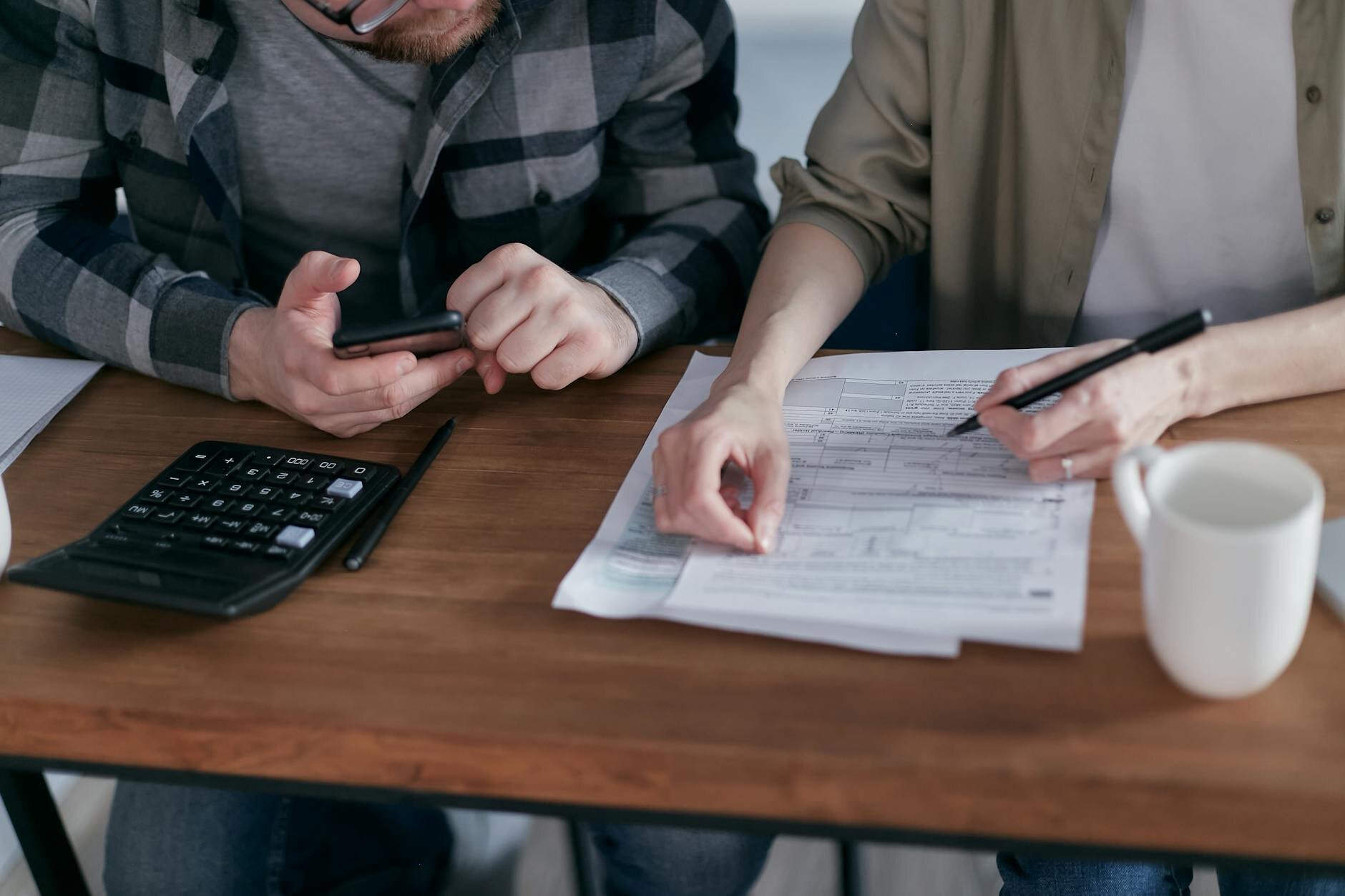 Business partners reviewing their gross qualifying income on paper records before beginning their step-by-step Making Tax Digital registration process.