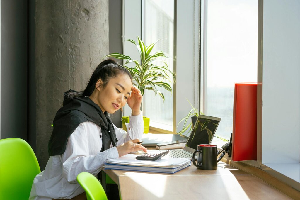 Young woman calculating finances at desk with calculator