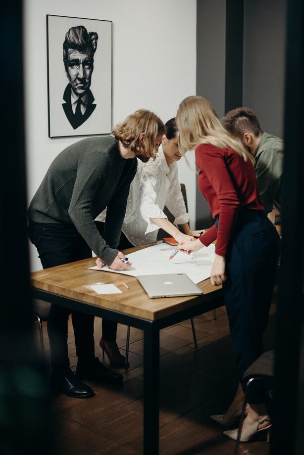 people gathered around a table with a big piece of paper