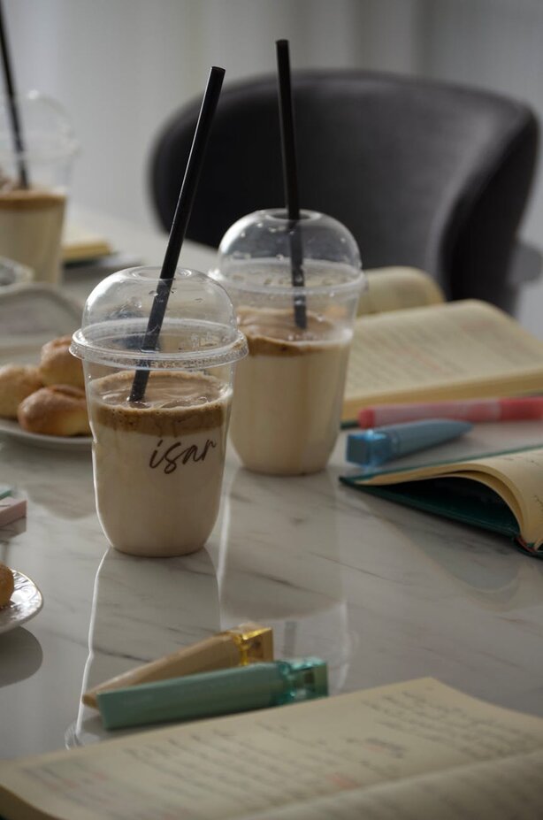 Two iced coffee drinks beside open books on table