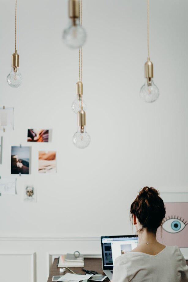 Woman working at desk under hanging Edison bulb lights
