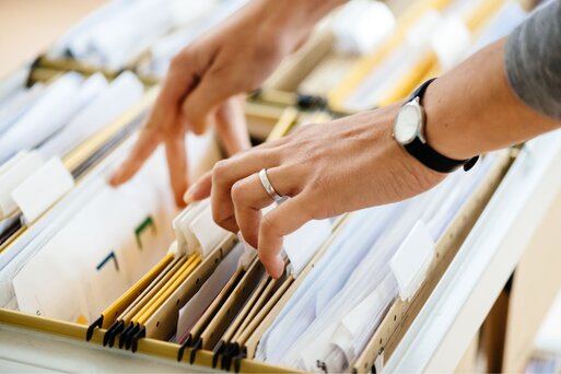 Hands searching through organized files in a cabinet