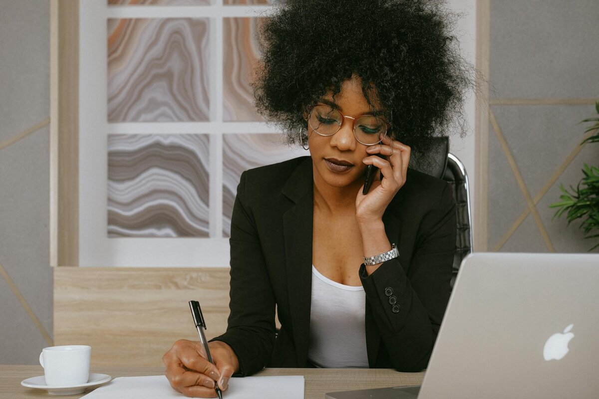 lady with her phone working on laptop