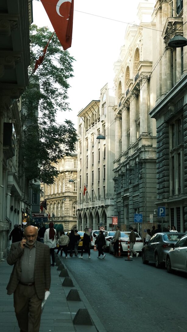 Man walking on busy street with Turkish flag overhead
