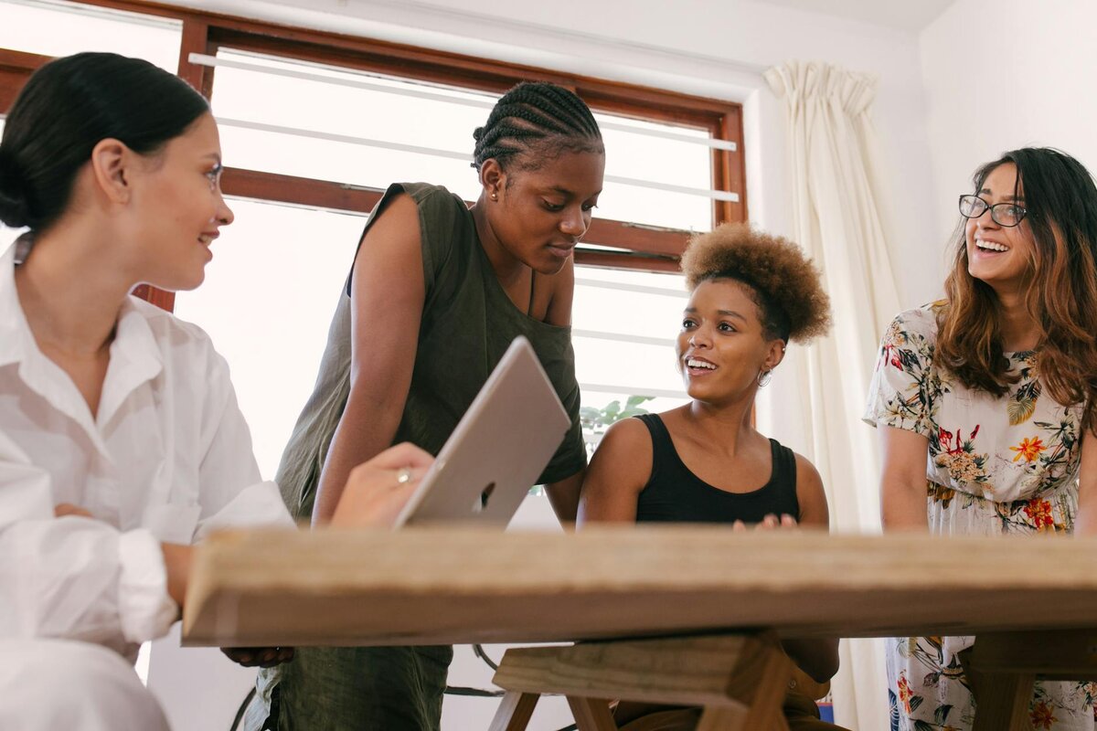 four women in a casual meeting sitting around a table 