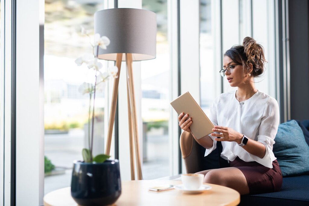 Businesswoman reading tablet while sitting by bright window