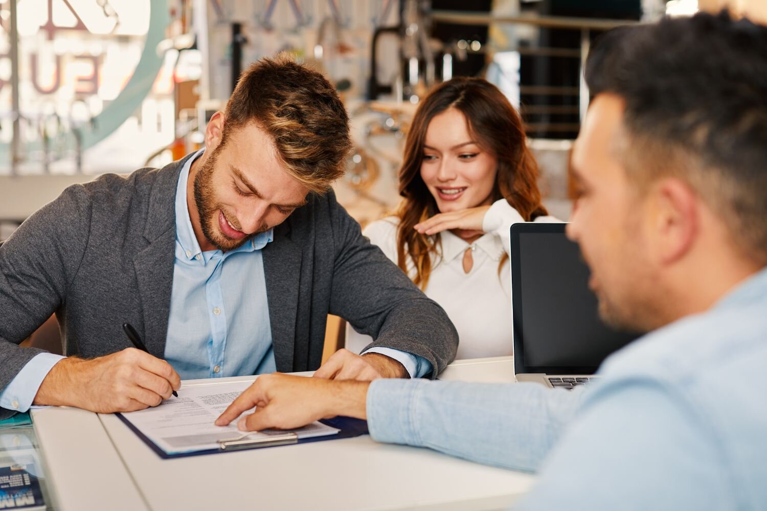 couple signing a paper  document while a man pointing
