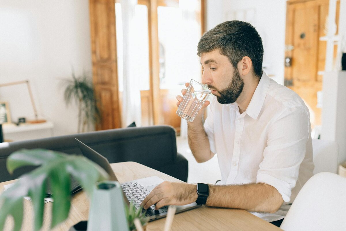 man on laptop drinking water