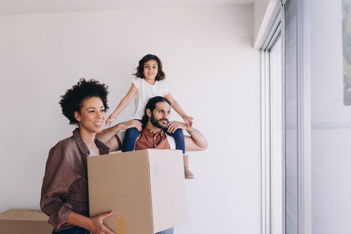 Family carrying moving boxes into new home together