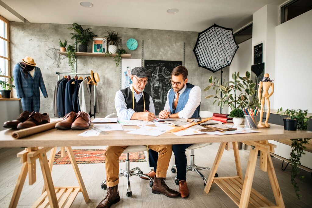 Two designers collaborating at desk in fashion studio