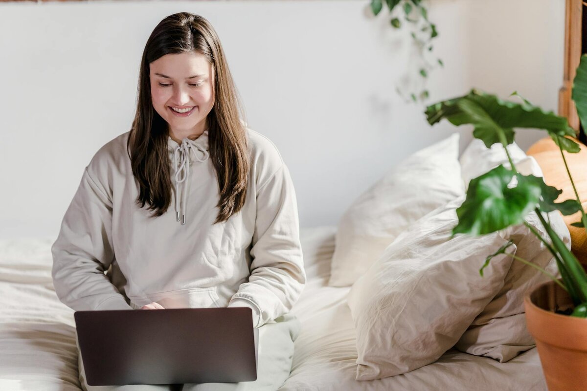 Happy lady on a bed with a laptop