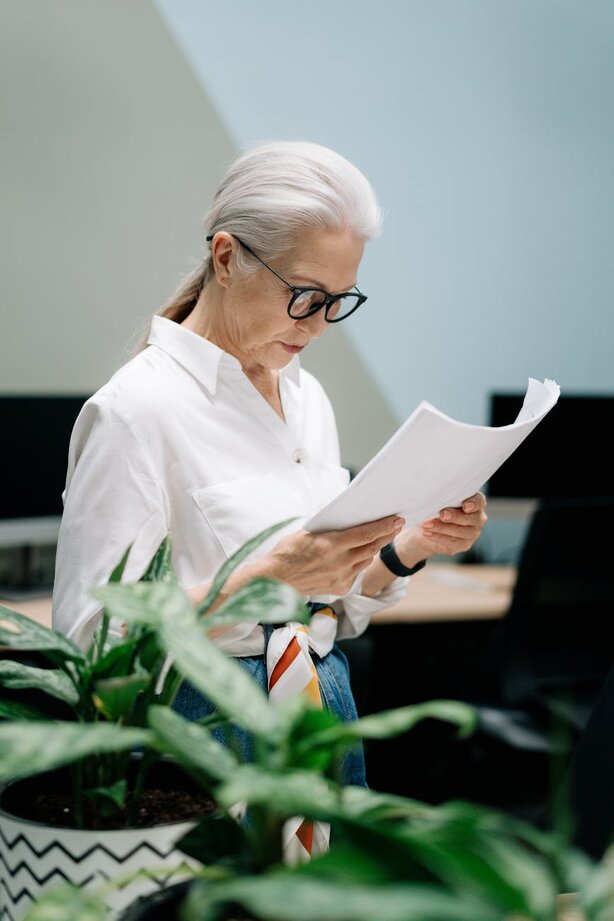 Older woman with white hair reading documents at office