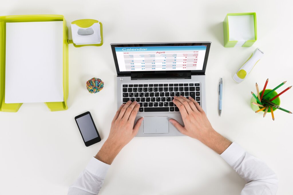 Hands typing on laptop with office desk items.