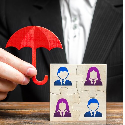 Hand holding red umbrella over puzzle pieces with people