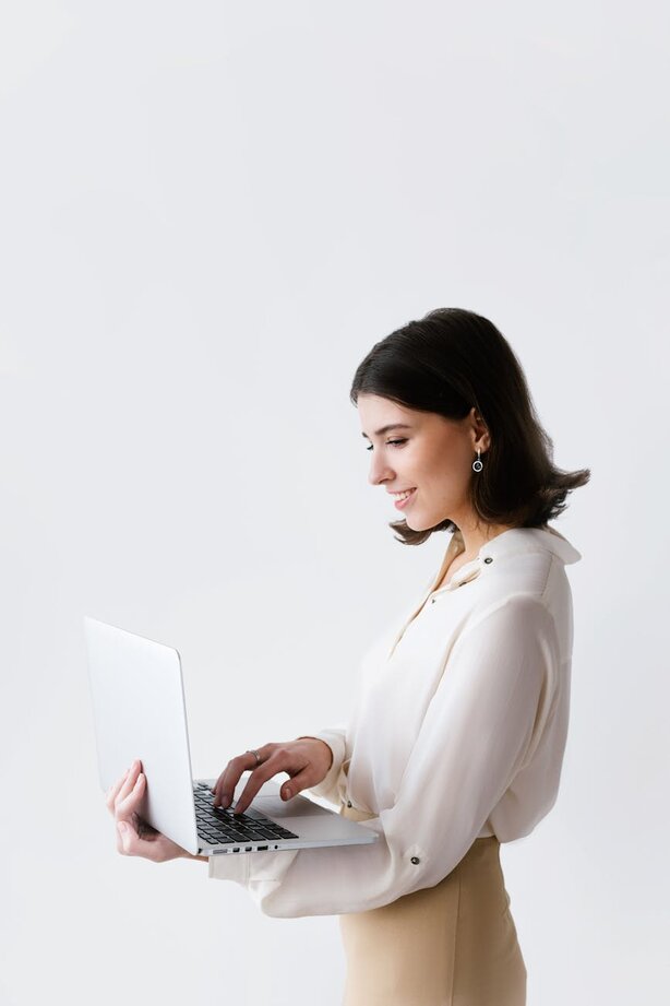 Businesswoman in white blouse holding and using laptop
