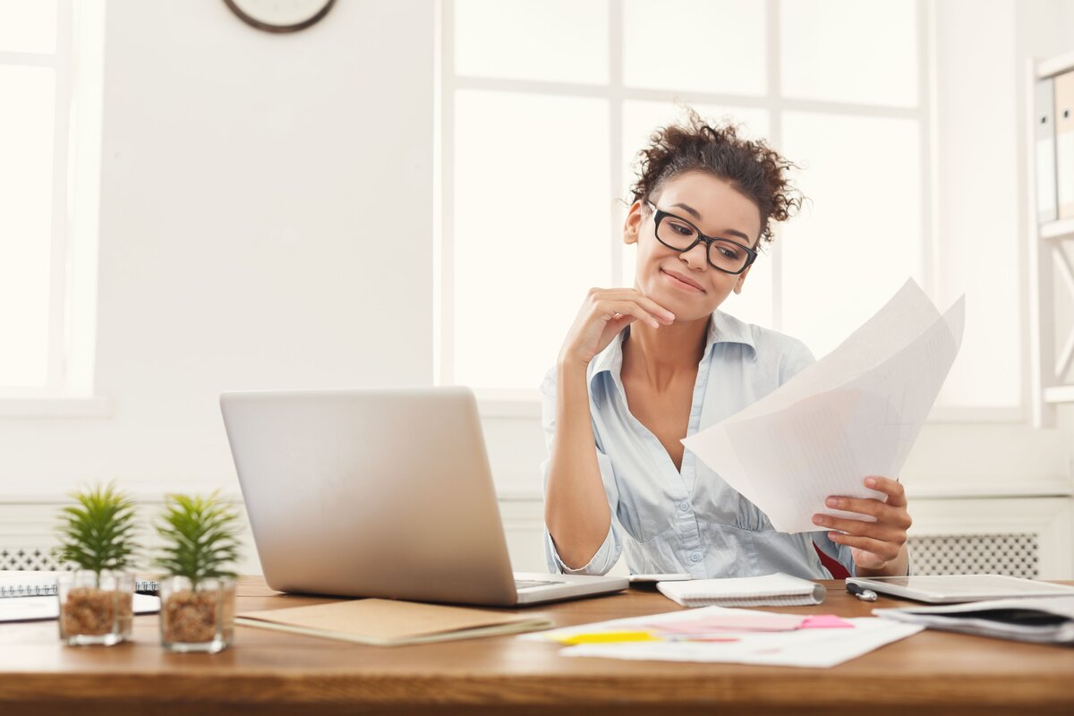 Woman reviewing tax documents while using a tax app on her laptop