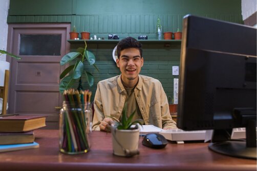 Smiling man sitting at office desk with computer