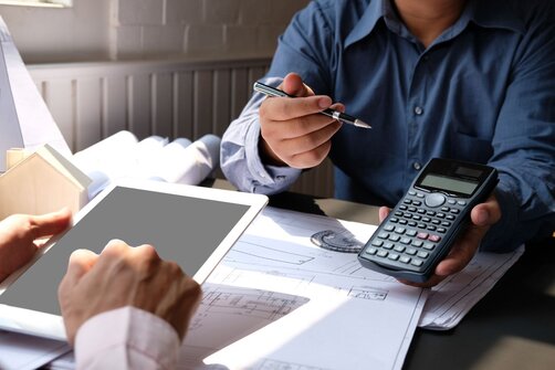 man with a calculator showing it to another holding a tablet