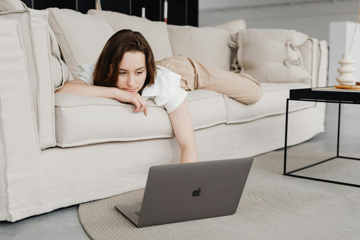 lady laying on sofa with her laptop