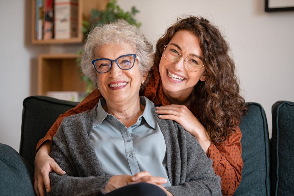 Two smiling women with glasses sitting together on couch