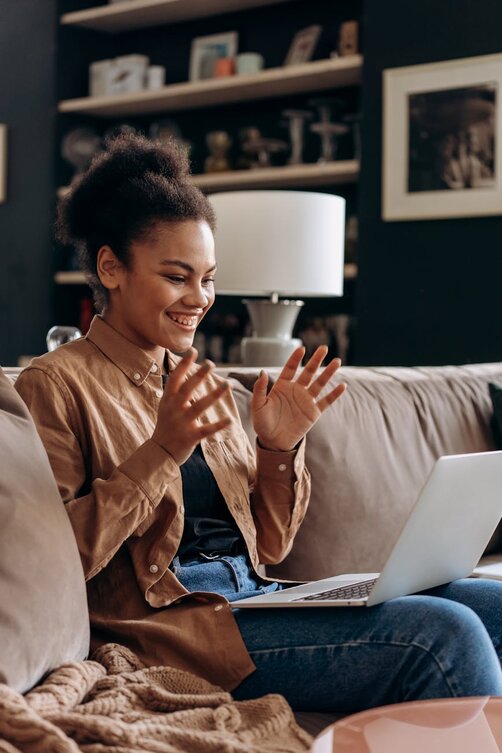 Happy woman waving during video call on laptop