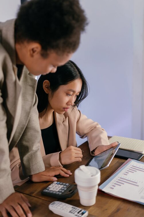 Two people reviewing documents and tablet at table
