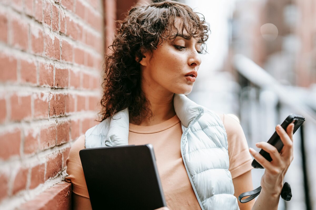 woman leaning on wall checking her phone 