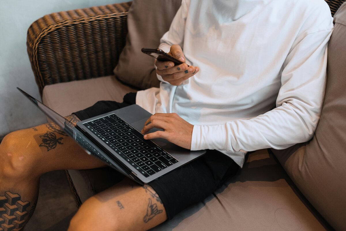 Man working on a laptop and checking their phone