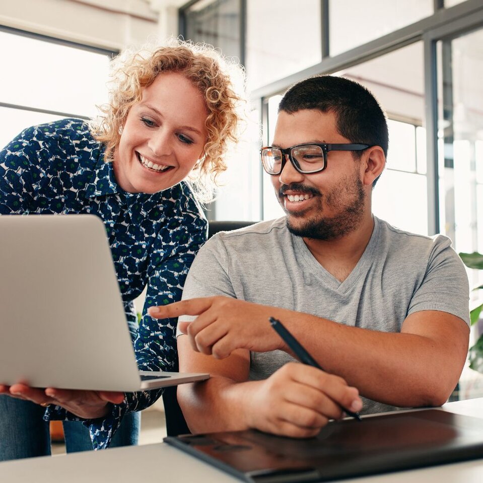 Colleagues reviewing work together on laptop in office