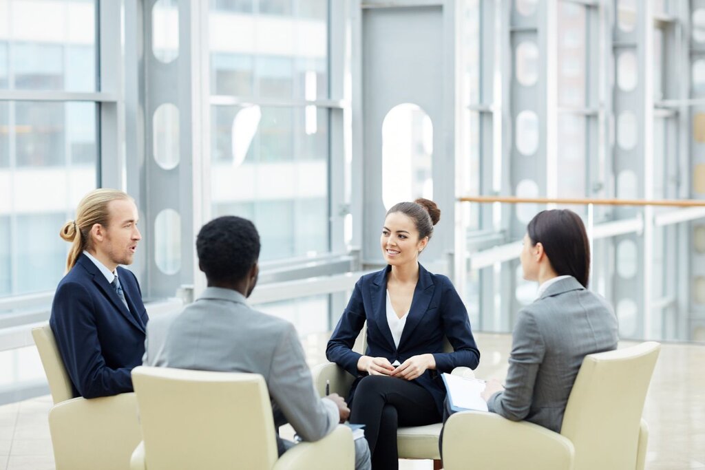 Four business professionals having discussion seated in modern lobby