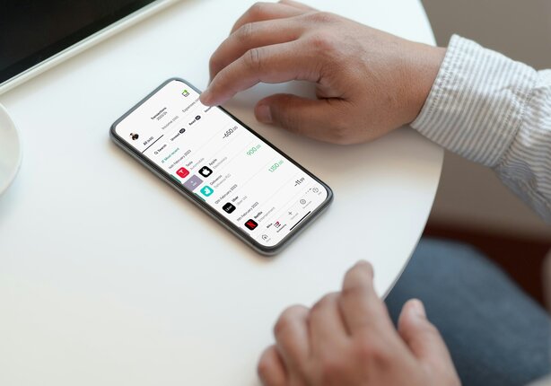 Hand using smartphone app while seated at table
