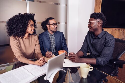 Three colleagues having a discussion around an office table