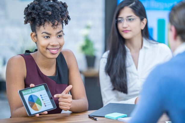 Woman presenting tablet with chart to colleagues in meeting