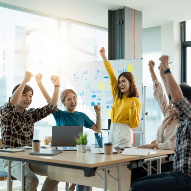 Diverse team celebrating success with raised fists in office