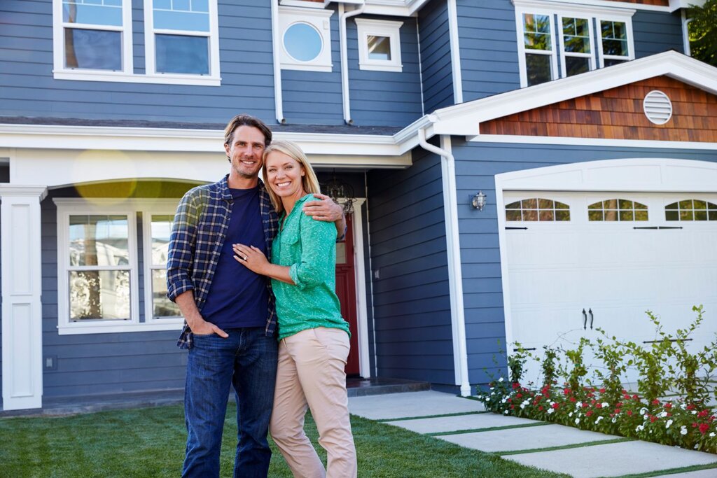 Smiling couple standing in front of new home