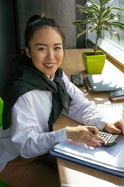 Young woman calculating finances at desk with laptop
